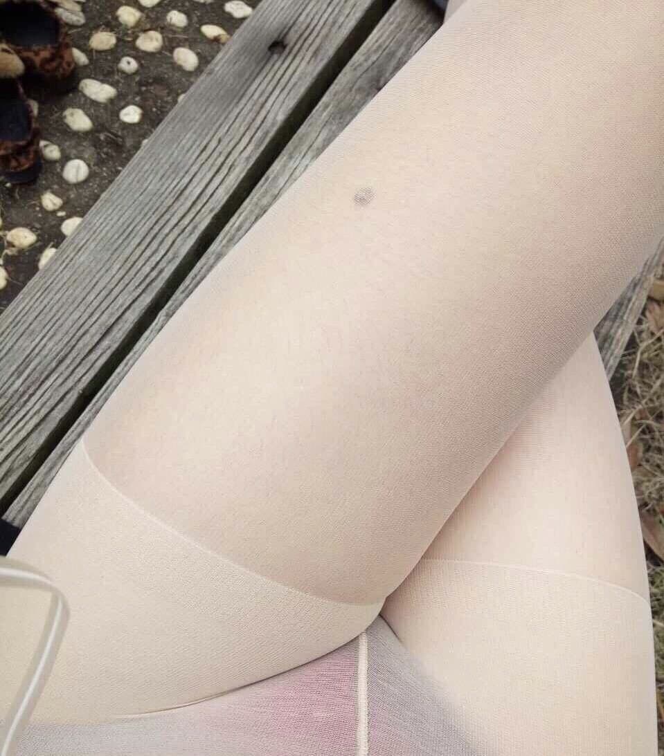 Sunlit park scene with nude pantyhose-clad legs relaxed on a checkered picnic blanket